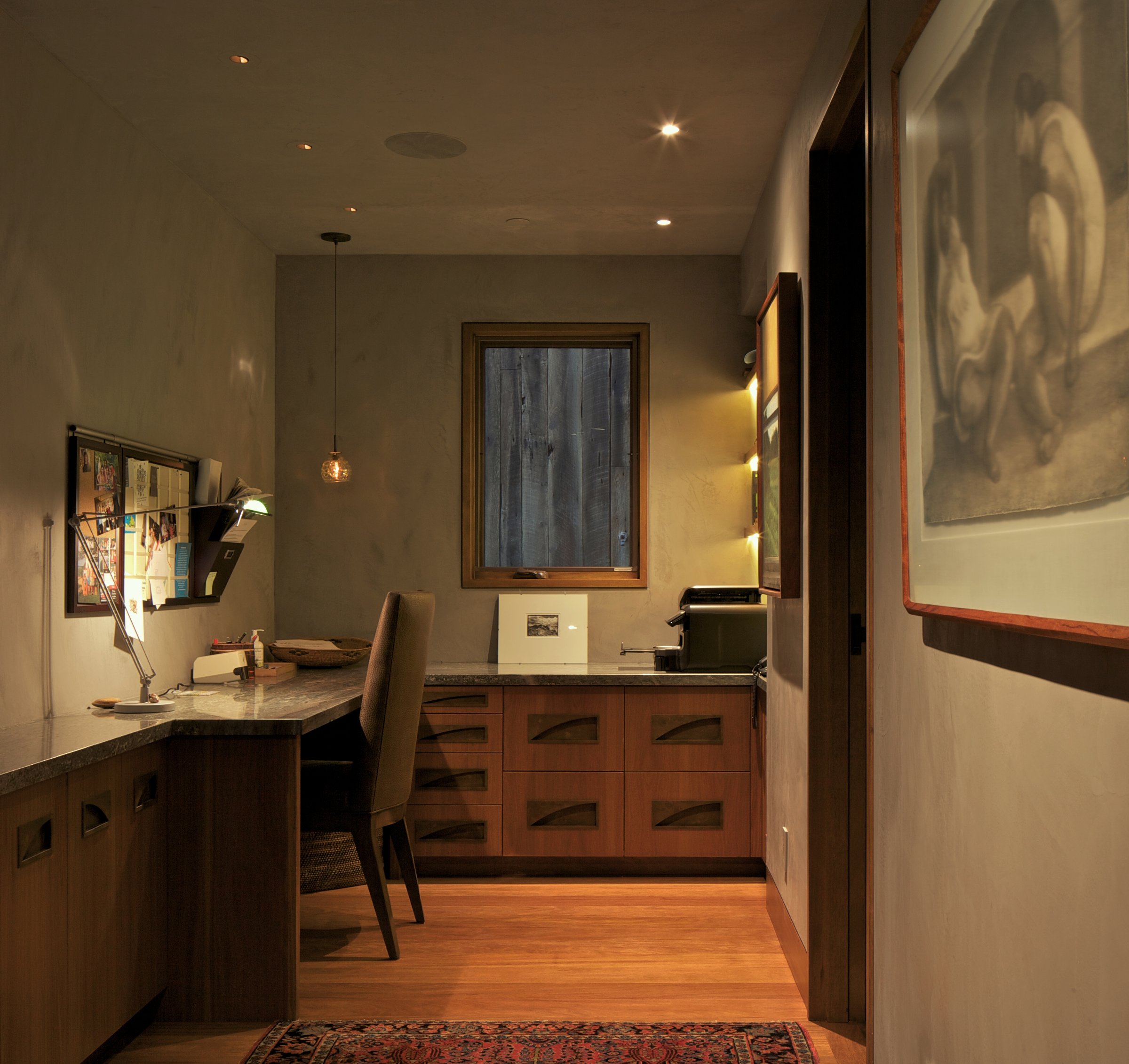 Moody home office nook with a pendant light, framed art, and a walnut built-in desk